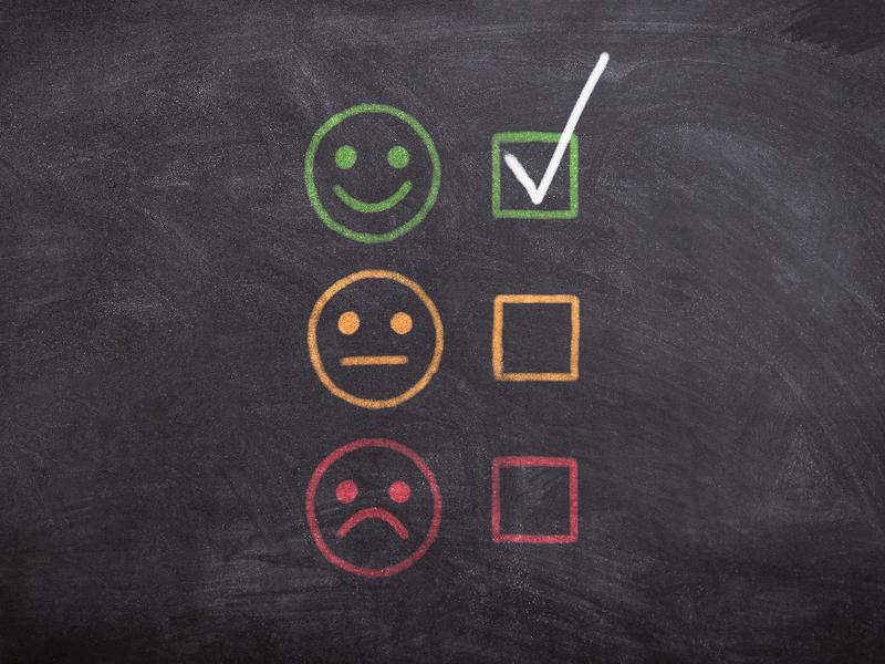Chalkboard with a green smiley face and a checkmark, a neutral face and no checkmark, and a frowning face with no checkmark